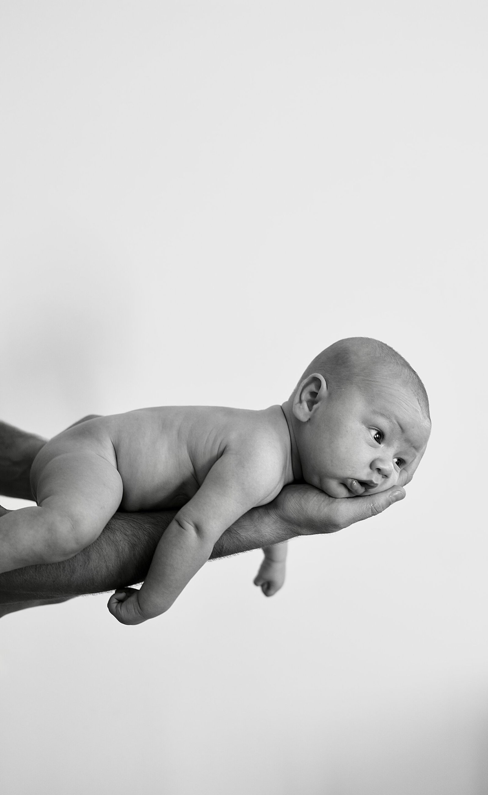 Photo de naissance noir et blanc, bébé sur le bras de son papa