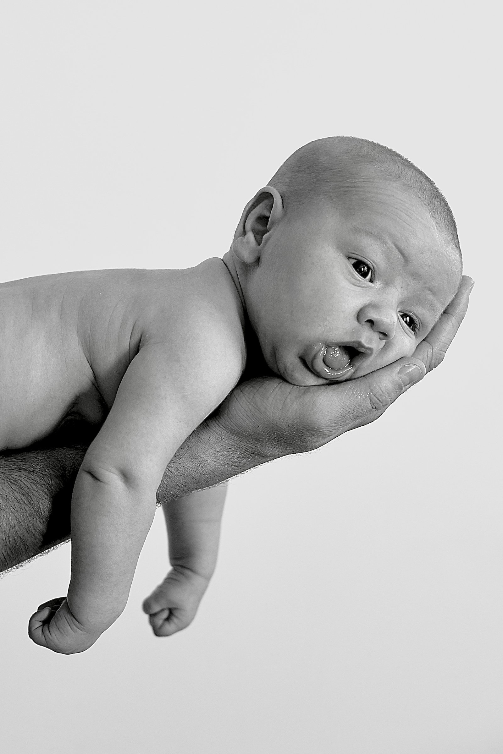 un nourrisson sur un bras qui fait la grimace 