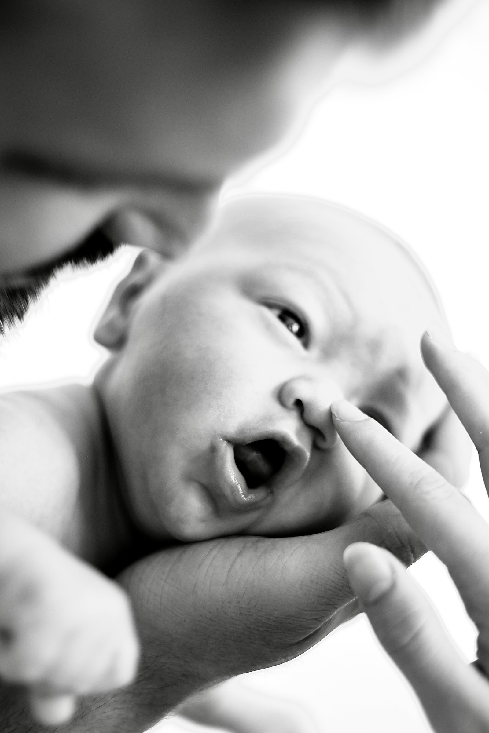 visage d'un nourrisson qui a le doigt de sa maman sur son nez