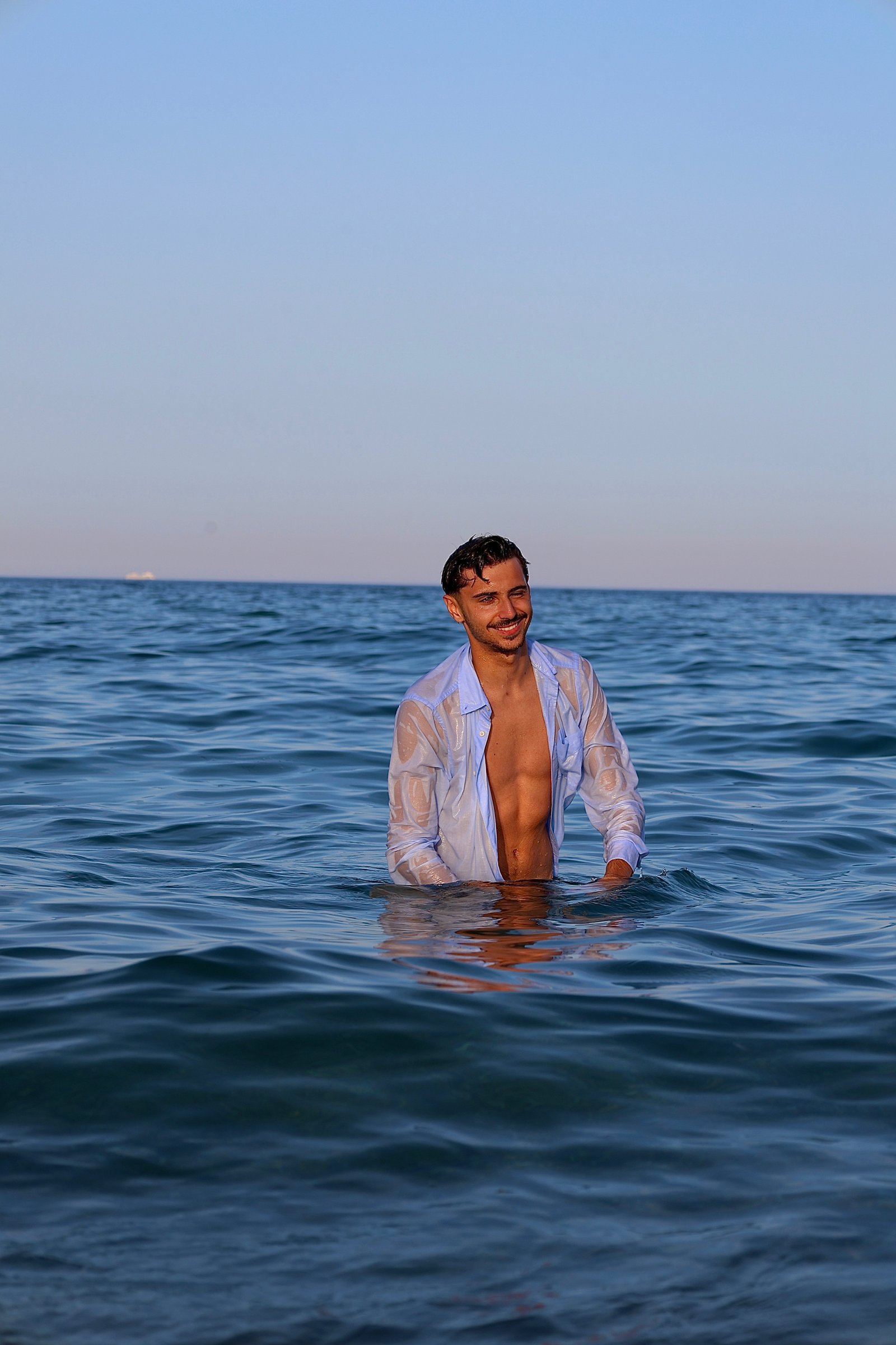 jeune homme au milieux de la mer en chemise 