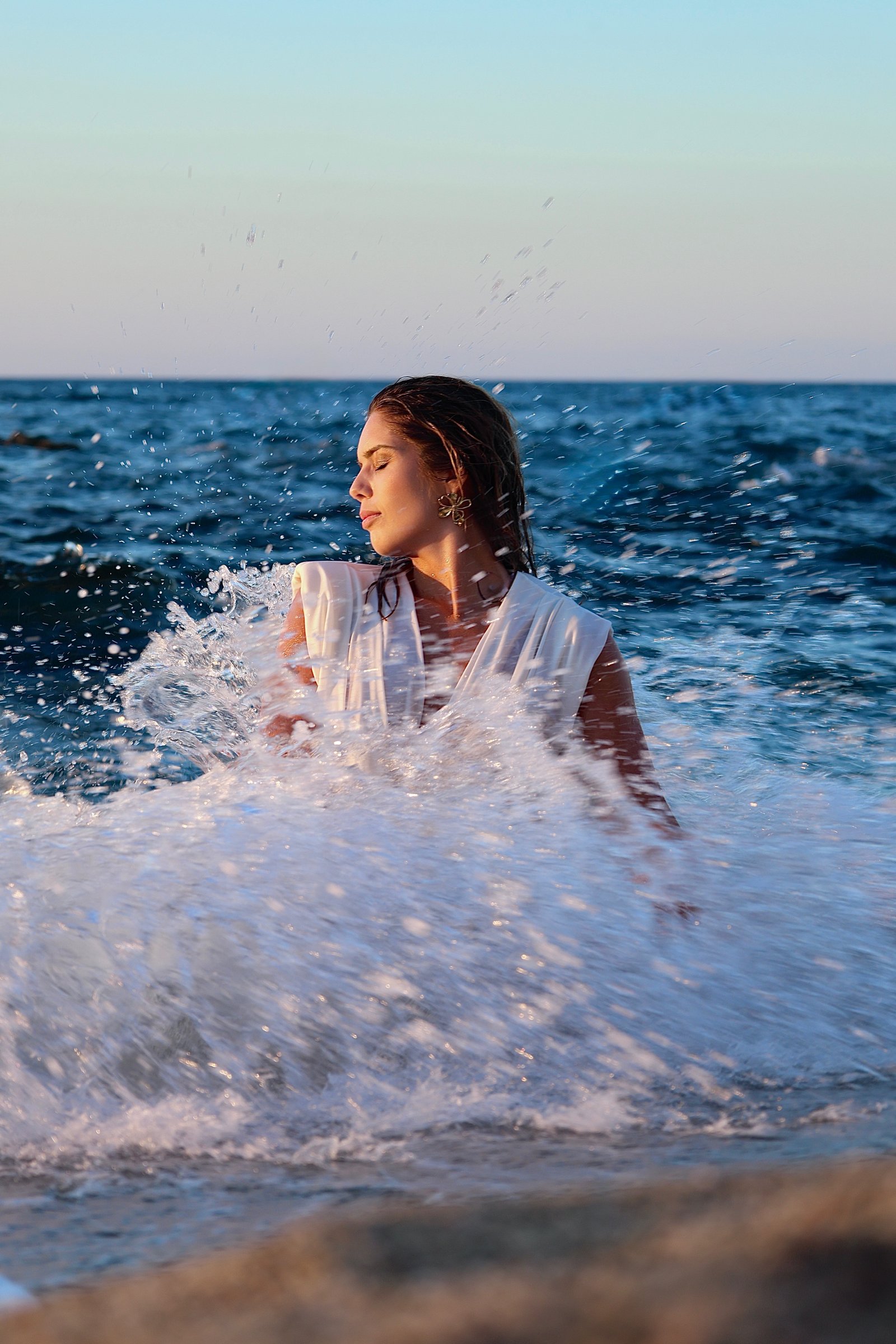jeune femme dans l'eau surprise par une vague 