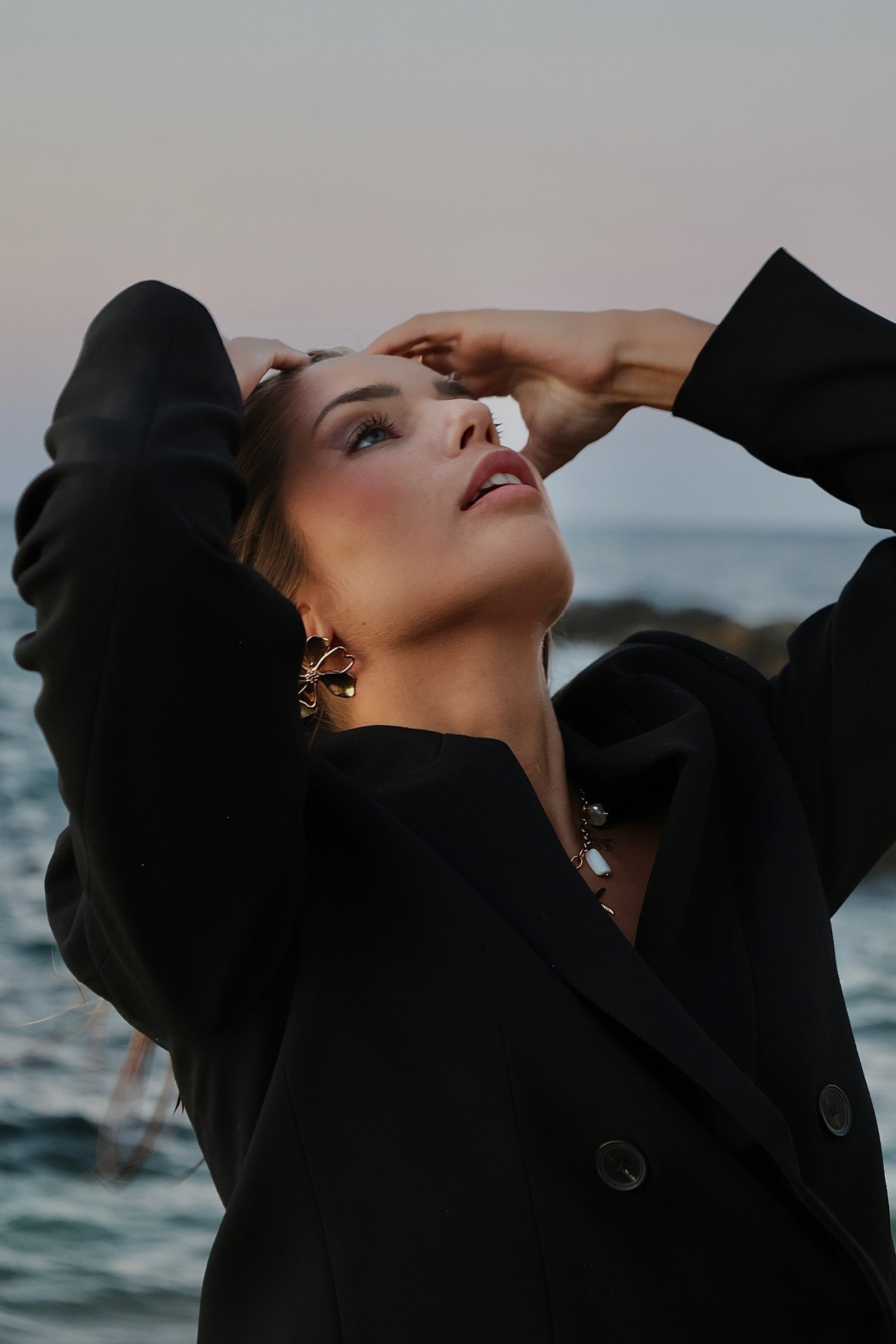 jeune femme face a la mer avec les mains dans le cheveux 