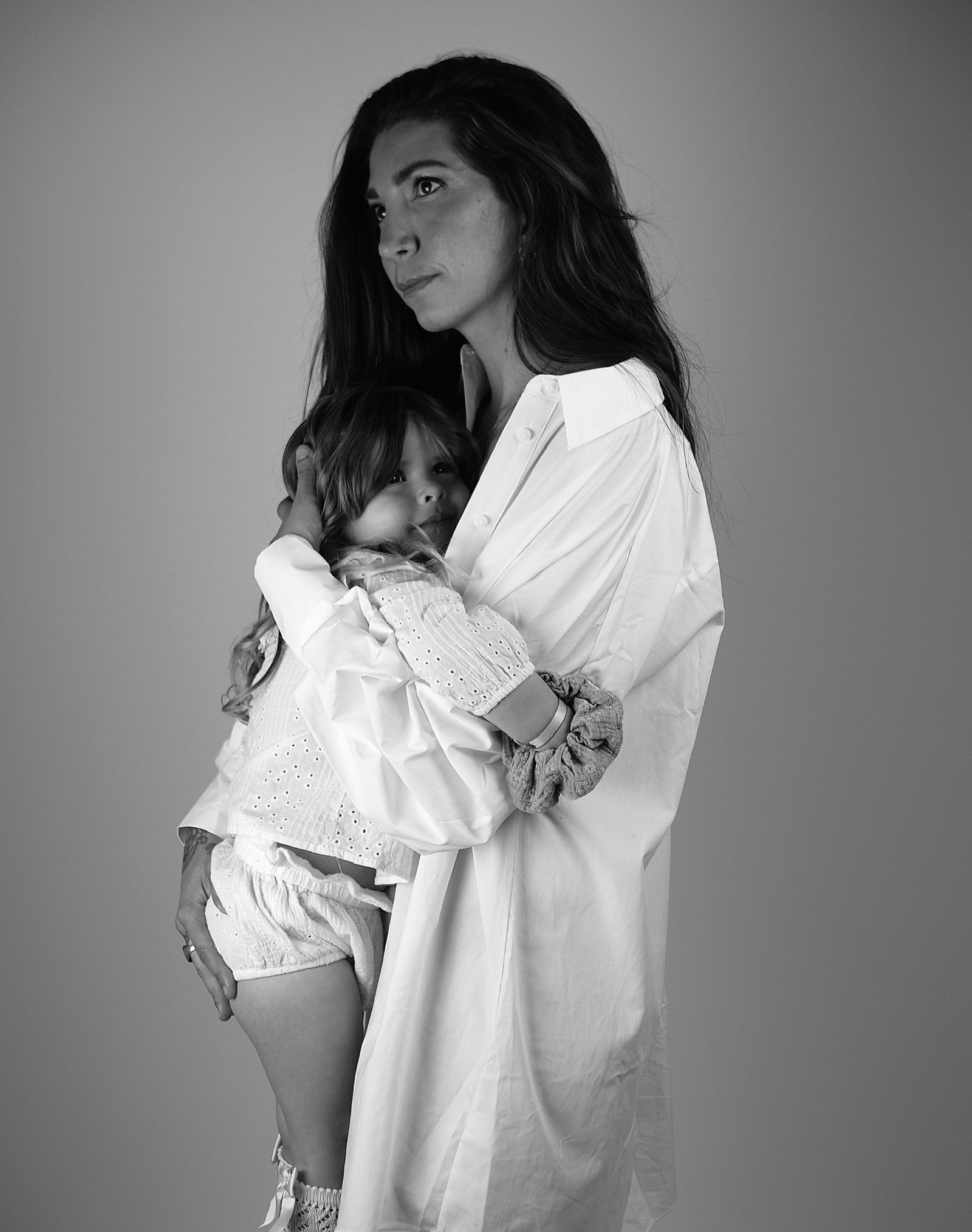 une maman portant sa fille dans ses bras contre elle 