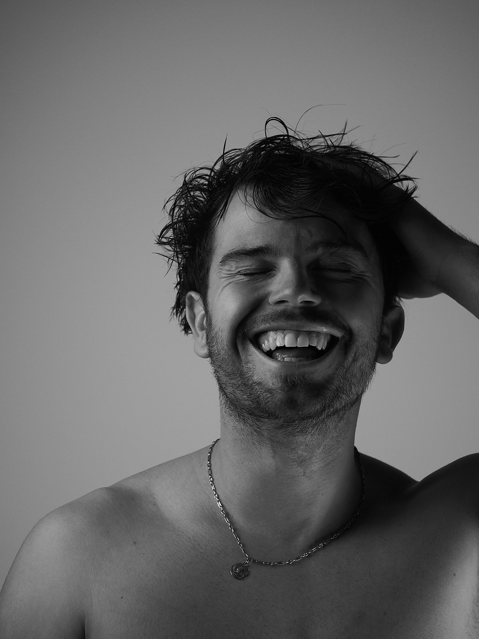 un jeune homme en éclat de rire main dans ses cheveux 