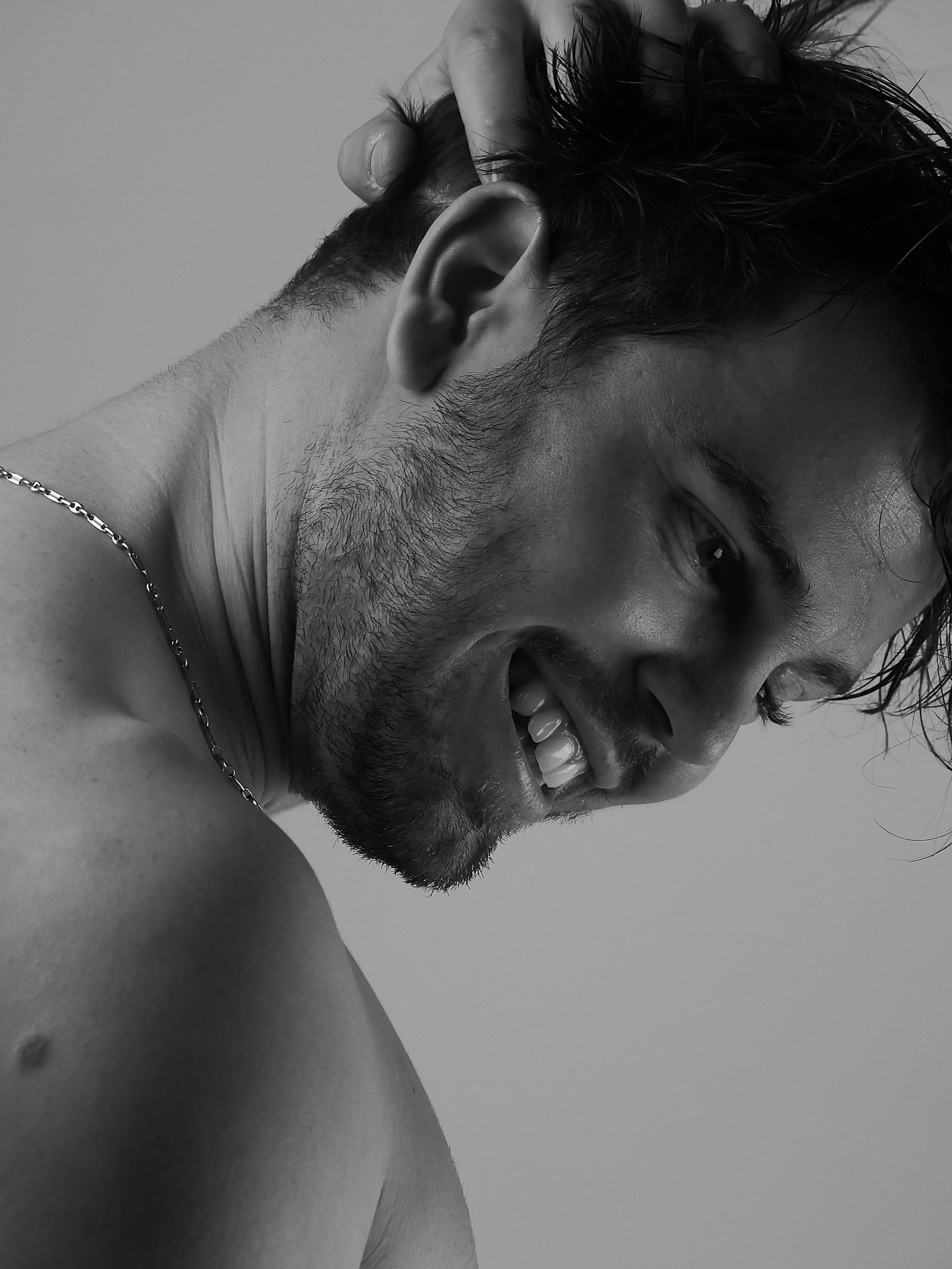 un jeune homme passant sa main dans ses cheveux et qui sourit 