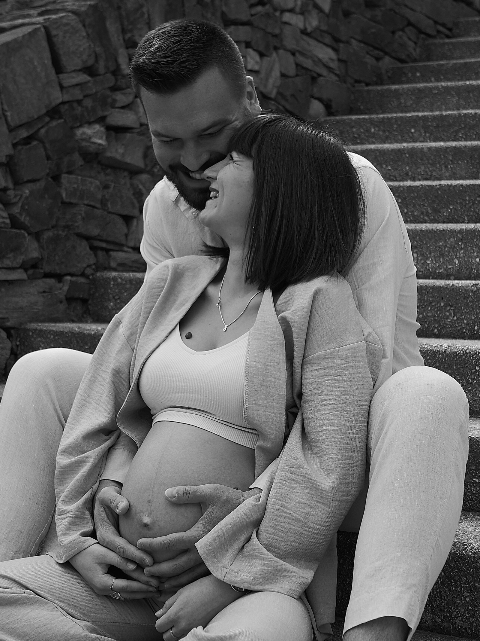 les futurs parents assis qui se regarde dans les yeux avec le futur papa qui soutien le ventre de la futur maman 