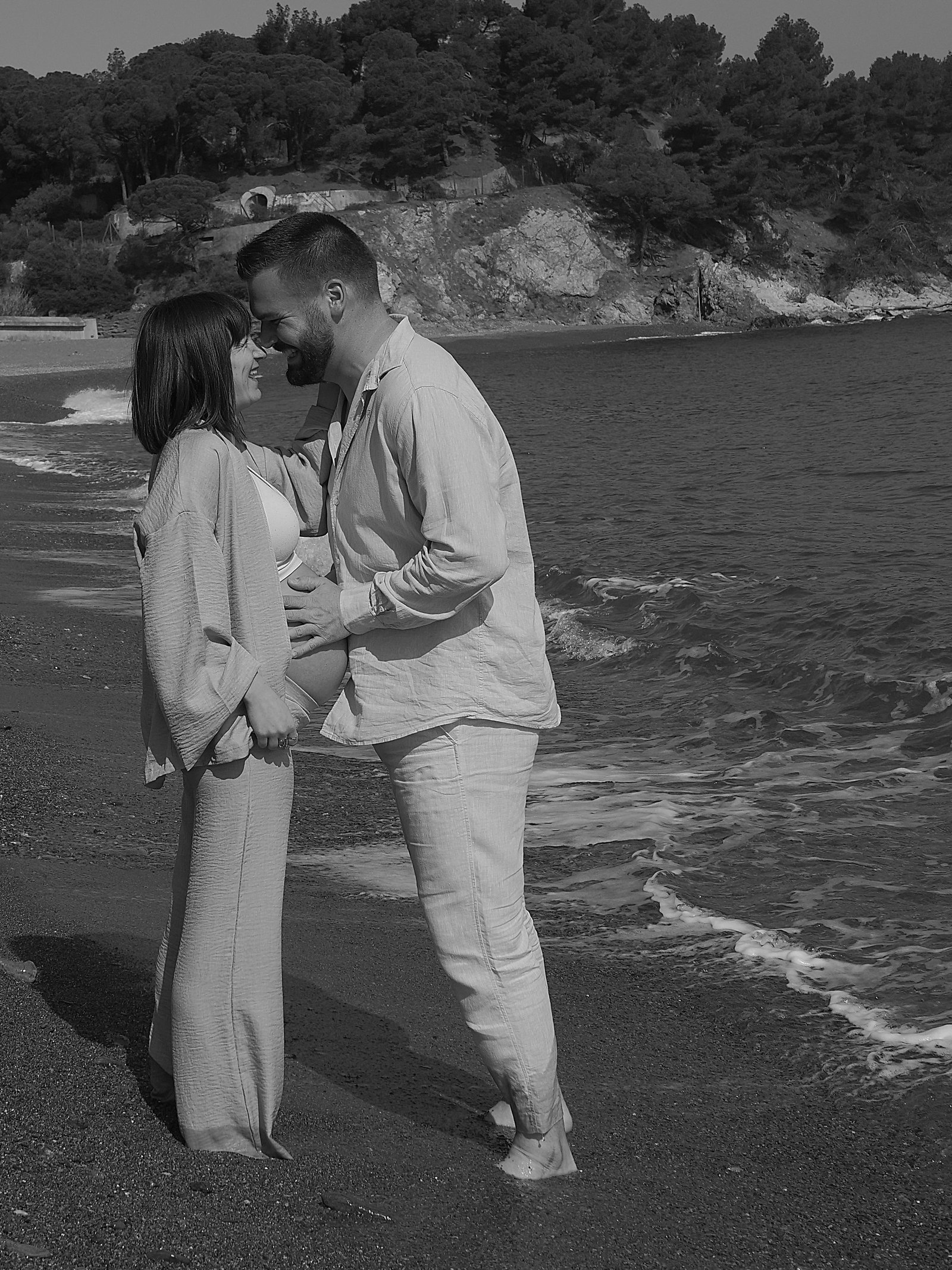 les futurs parents en train de se regarder dans les yeux en bord de plage 
